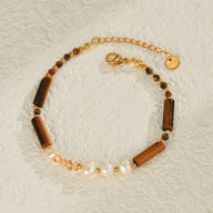 Bracelet doré avec perles blanches et pierres rectangulaires œil de tigre scintillantes.