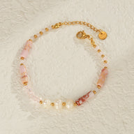 Bracelet femme avec perles dorées et pierres naturelles rose pâle sur chaîne fine dorée ajustable.