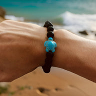 Bracelet mixte en pierre volcanique noire avec tortue turquoise sculptée au centre.