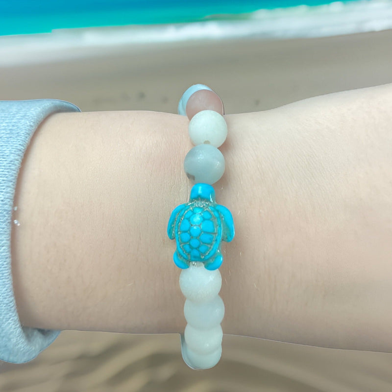 Bracelet mixte en pierre blanche avec une tortue turquoise sculptée au centre.