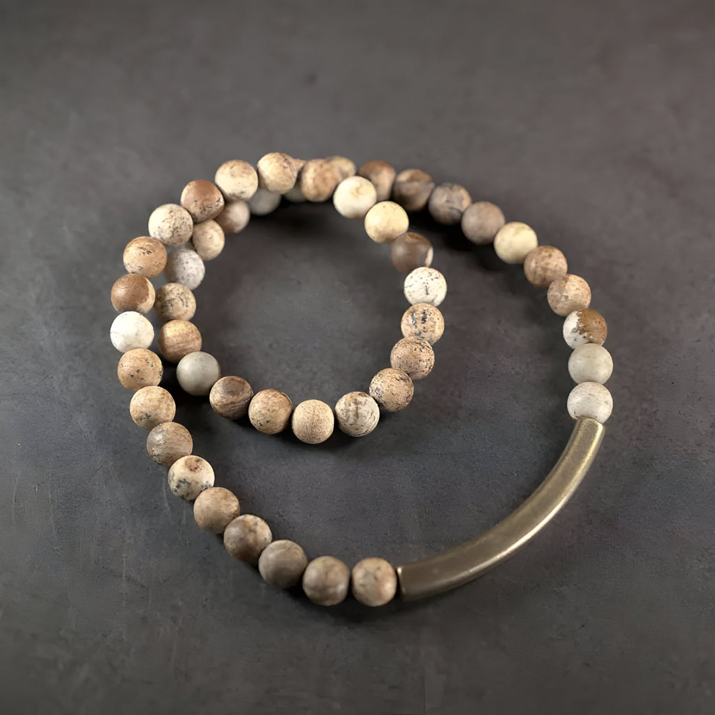 Bracelet mixte de perles rondes en pierre volcanique marron clair avec barre en cuivre courbée.