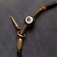 Bracelet en cuivre et agate noir avec perles dorées et détail rouge, fermoir conique.