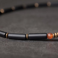 Bracelet femme en pierres d'agate noires cylindriques, perles cuivre doré, et agate orange translucide.