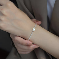 Bracelet fin en perles blanches avec pendentif tête de chat en cristal transparent.