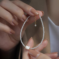 Bracelet femme perles blanches fines avec tête de chat en nacre et chaîne dorée réglable.