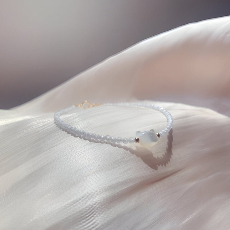 Bracelet fin en pierres de cristal blanches avec pendentif tête de chat blanche brillante.