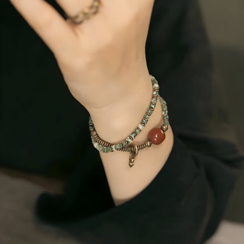 Bracelet double tour en jaspe et agate bleue avec pendentif serpent en cuivre sur poignet féminin.