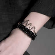 Bracelet multi-couches pour femme avec perles cubiques en onyx noir et fil ondulé en cuivre.