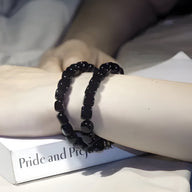 Bracelet Mina multi-couches en pierres d'onyx cubiques noires porté sur poignet féminin.