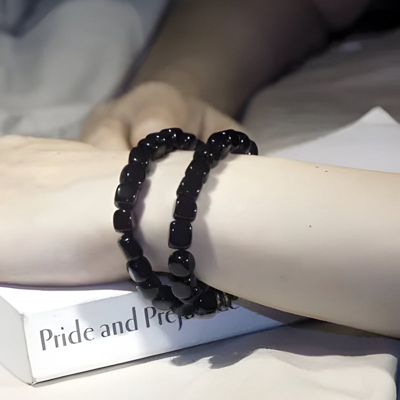 Bracelet Mina multi-couches en pierres d'onyx cubiques noires porté sur poignet féminin.