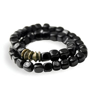 Bracelet multi-couches en pierres d'onyx cubiques noires avec détails en cuivre doré.