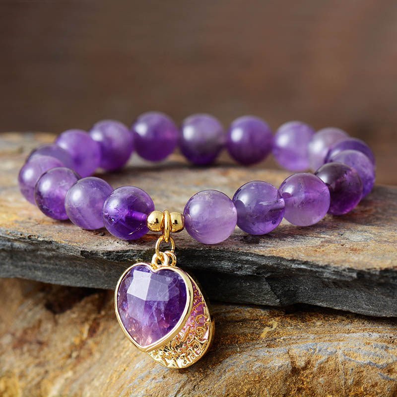 Bracelet élastique en améthyste violette 10mm avec pendentif charme en forme de cœur doré.