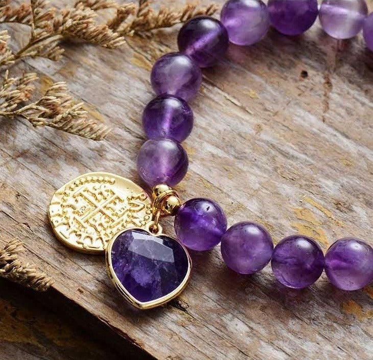 Bracelet élastique en perles d’améthyste 10mm avec pendentif cœur facetté violet et médaille dorée gravée.