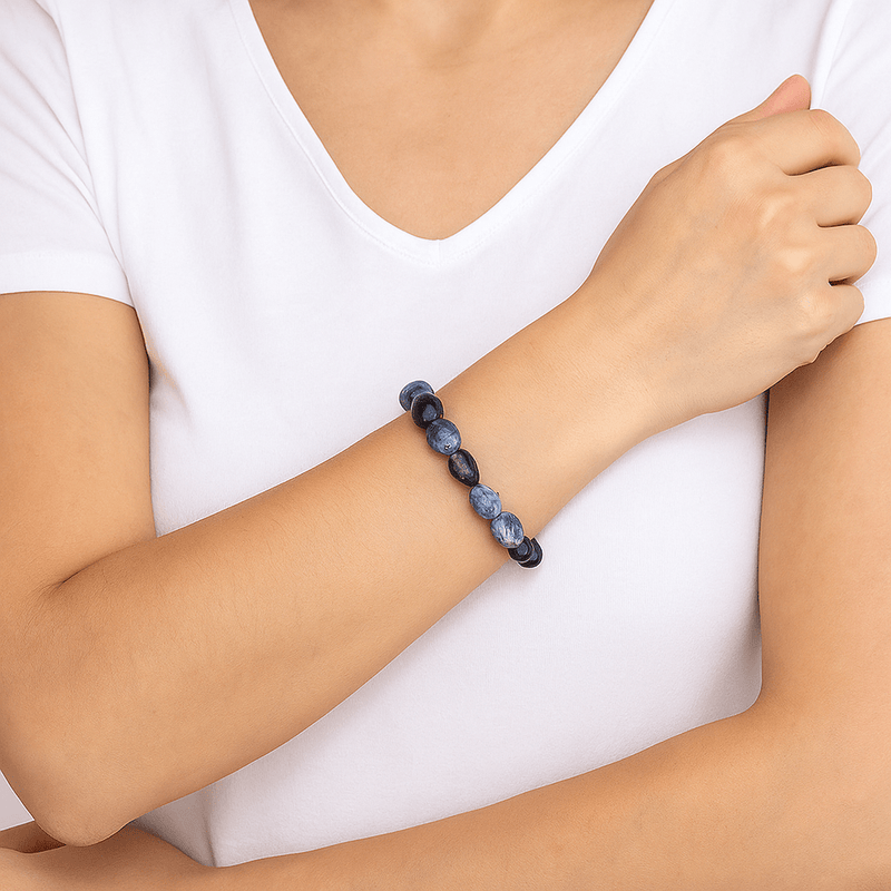 Bracelet Evolet en pierres naturelles bleu foncé, perles rondes, style asymétrique sur poignet féminin.