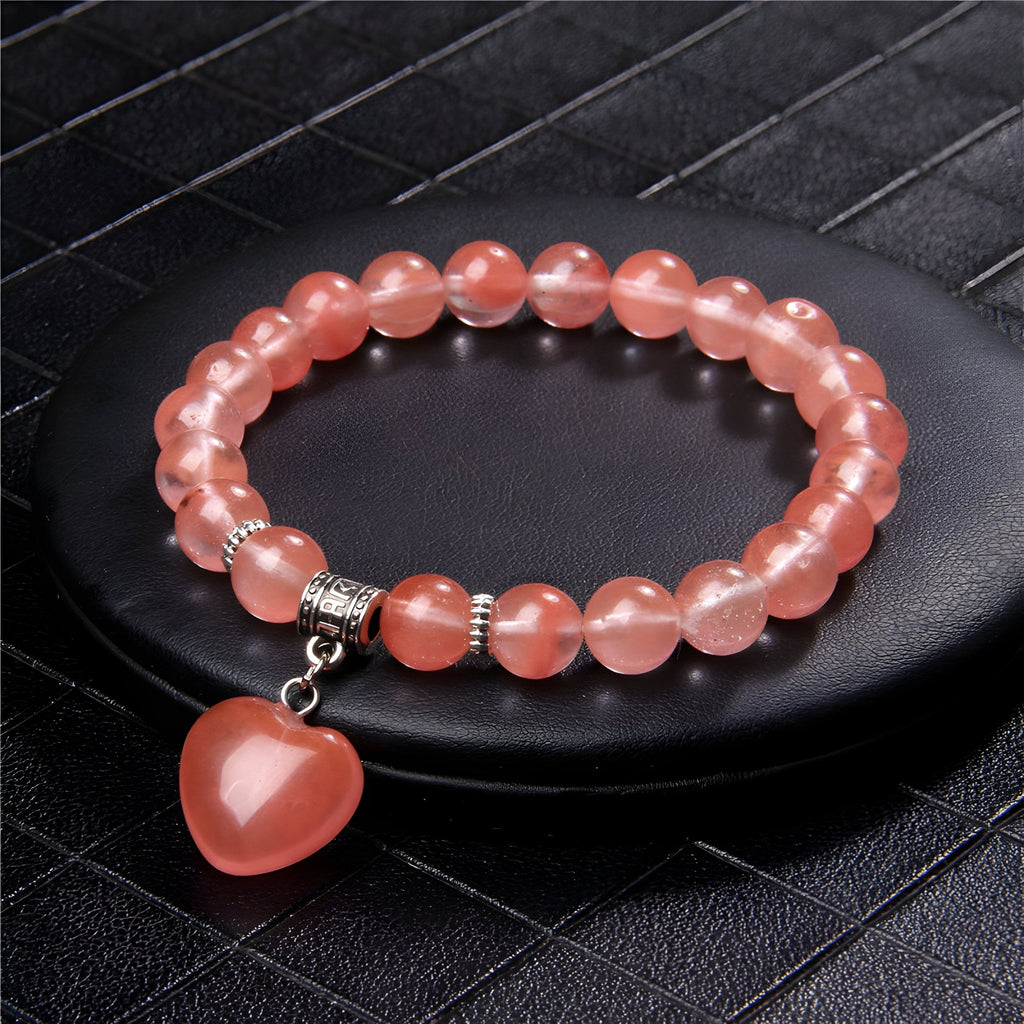 Bracelet mixte en pierres naturelles rose translucide avec pendentif cœur assorti et perles argentées.
