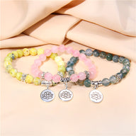 Lot de trois bracelets en pierres naturelles jaune, rose et vert avec pendentifs fleur de lotus argentés.