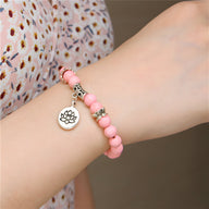 Bracelet mixte en perles roses quartz avec charm fleur de lotus en métal argenté.