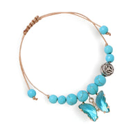 Bracelet ajustable en cordon beige avec perles turquoise lisses et charm papillon bleu en métal argenté.