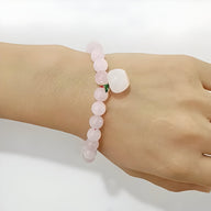 Bracelet mixte en quartz rose avec perles rondes et charm pomme blanche en pierre naturelle.