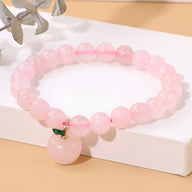 Bracelet en perles rondes de quartz rose avec charm pomme rose et détail vert en métal doré.
