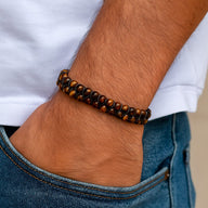 Bracelet double rang en pierres naturelles œil de tigre sur poignet masculin avec jean bleu.