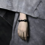 Bracelet femme en pierres naturelles noires et bois d’ébène tressé sur poignet.