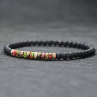 Bracelet fin pour homme en perles noires mates avec pierres naturelles multicolores centrées.