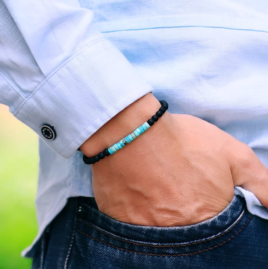 Bracelet fin pour homme en pierres naturelles turquoise et noires, style perles rondes, porté au poignet avec chemise.