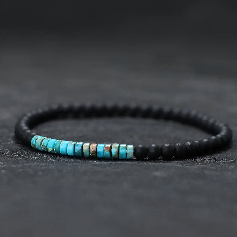 Bracelet fin pour homme en pierres naturelles noires et turquoises sur fil élastique.
