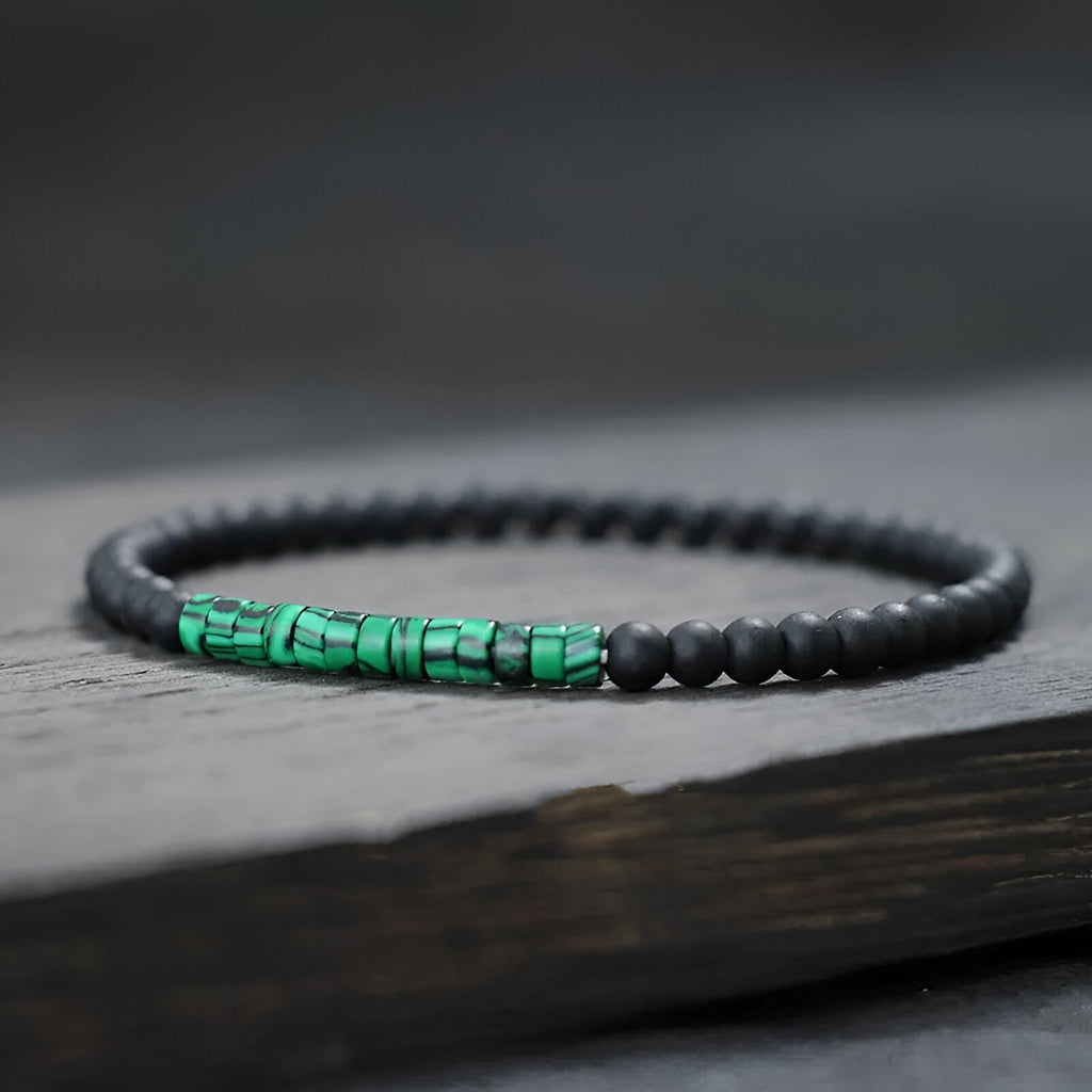 Bracelet fin pour homme en perles noires mates avec accent en pierres malachite vertes éclatantes.