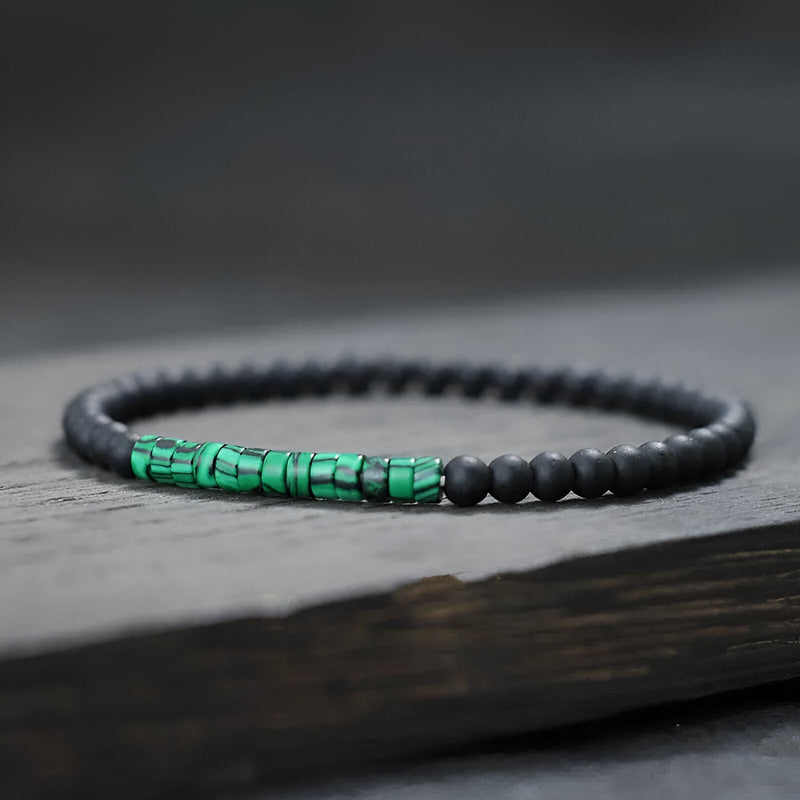 Bracelet fin pour homme en perles noires mates avec accent en pierres malachite vertes éclatantes.