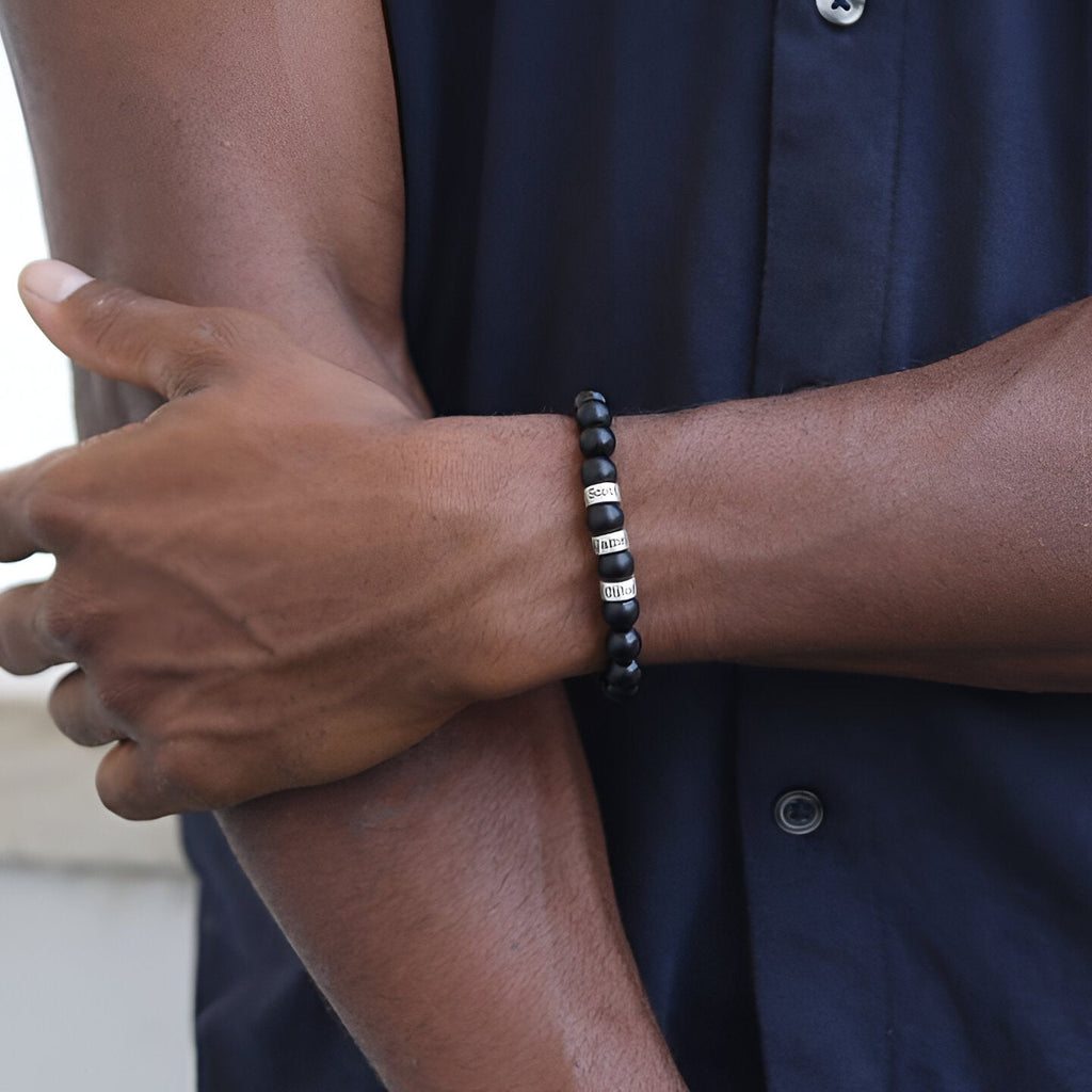 Bracelet homme en perles d'onyx noir mat avec trois plaques métalliques argentées, style minimaliste.