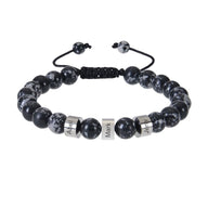 Bracelet en pierres naturelles noires avec perles éclatées blanches, trois plaques argentées gravées, cordon réglable noir.