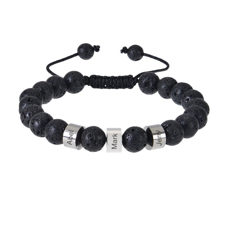 Bracelet en pierres volcaniques noires avec trois plaques argentées gravées et fermeture coulissante noire.