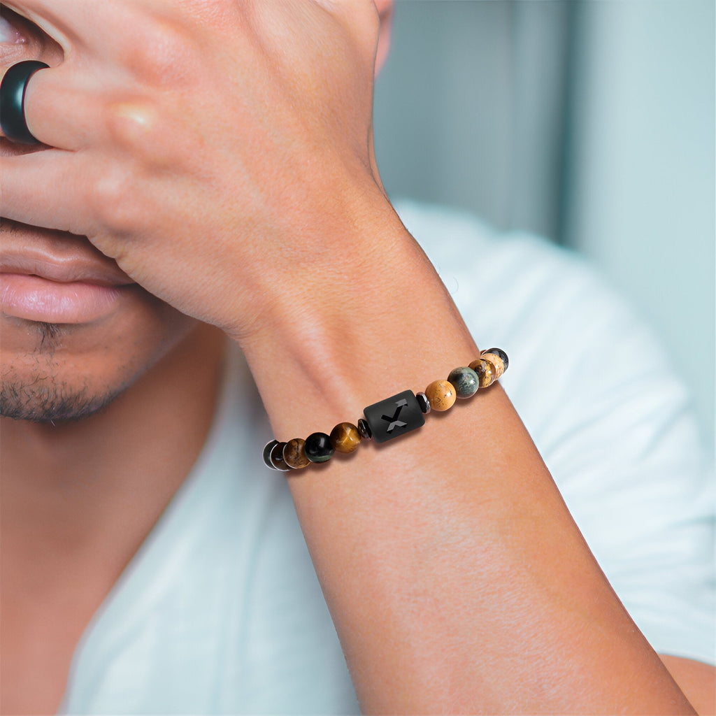 Bracelet mixte en pierres naturelles avec pendentif noir sculpté, porté au poignet homme.