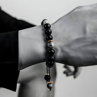 Bracelet homme en pierres naturelles noires style volcanique avec perles grises et accents dorés.