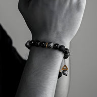 Bracelet pour homme en pierres naturelles noires volcaniques avec perles lisses et finition pendentif en métal doré.