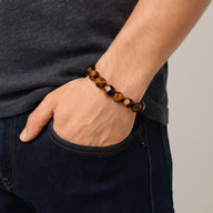 Bracelet Aerith en pierres naturelles taillées œil de tigre aux tons marron et noir porté au poignet.