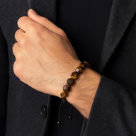 Bracelet ajustable en pierres naturelles taillées œil de tigre aux tons bruns et dorés sur poignet masculin.