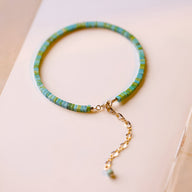 Bracelet femme en pierres turquoises et vertes avec chaînette dorée ajustable.