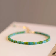 Bracelet fin en pierres turquoise et vertes carrées avec fermoir doré simple.