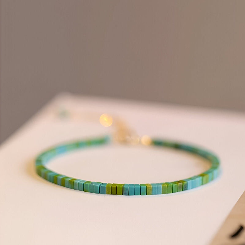 Bracelet fin en pierres turquoise et vertes carrées avec fermoir doré simple.