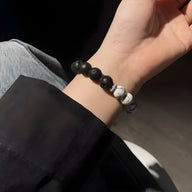 Bracelet mixte en pierres volcaniques bi-colores noir et blanc sur poignet, style moderne et naturel.