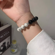 Bracelet mixte en pierres volcaniques noires et blanches, perles rondes lisses, style moderne.