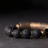 Bracelet femme en pierres volcaniques noires et laiton doré, style ancien, cordon marron tressé.