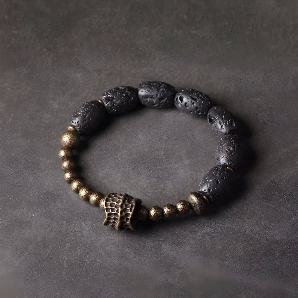 Bracelet femme en pierres volcaniques noires et perles en laiton doré avec détail central texturé.