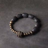 Bracelet femme en pierres volcaniques noires et perles en laiton doré avec détail central texturé.