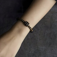 Bracelet femme en perles noires de pierre volcanique avec détails en laiton doré, modèle Drita, 18 cm.