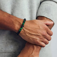 Bracelet masculin en pierres volcaniques noires et œil de tigre vert avec tête de loup argentée.
