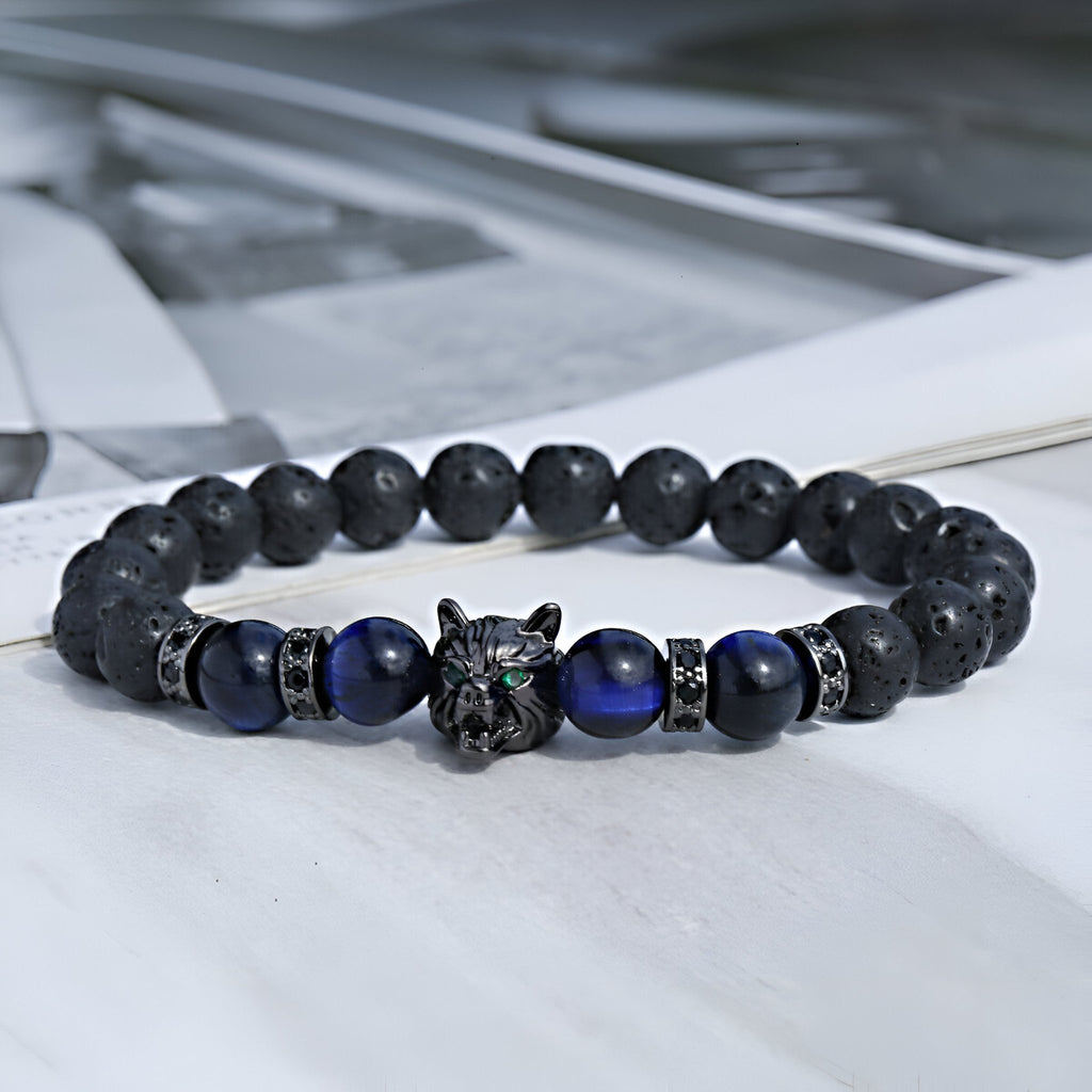 Bracelet masculin en pierres volcaniques noires et perles œil de tigre bleu avec tête de loup métallique détaillée.